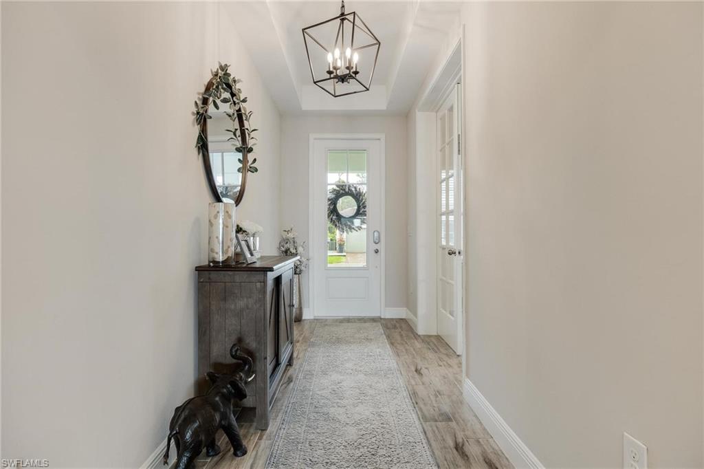 3621 Pilot Circle Naples, FL 34120 - Photo 4 of 46 a view of a hallway with wooden floor and a chandelier