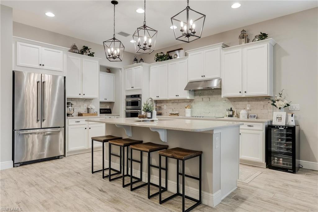 3621 Pilot Circle Naples, FL 34120 - Photo 6 of 46 a kitchen with stainless steel appliances granite countertop a refrigerator a sink dishwasher a stove and white cabinets with wooden floor