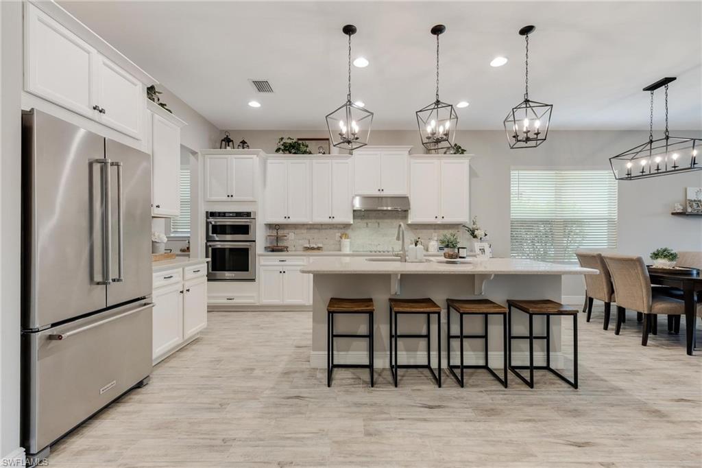 3621 Pilot Circle Naples, FL 34120 - Photo 8 of 46 a kitchen with stainless steel appliances granite countertop a sink a stove a refrigerator and island with wooden floor