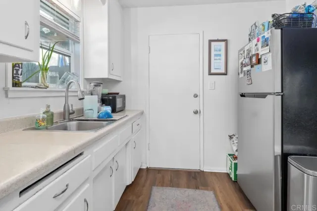 a kitchen with stainless steel appliances granite countertop a sink dishwasher stove and white cabinets with wooden floor