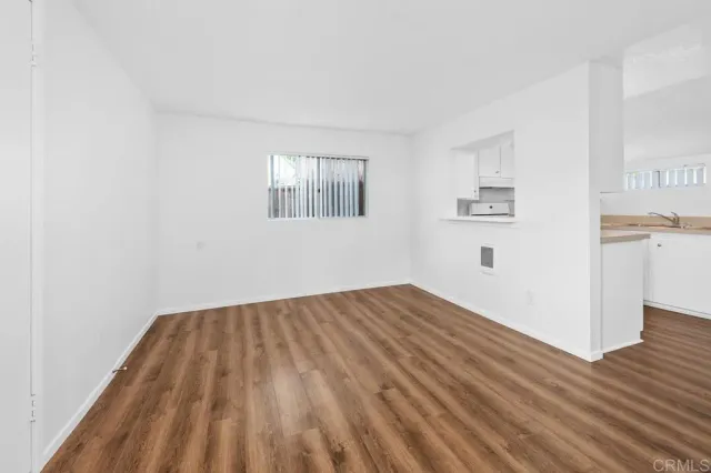 a view of a room with wooden floor and a kitchen space