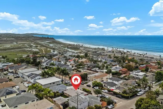 an aerial view of a city with lots of residential buildings ocean and mountain view in back