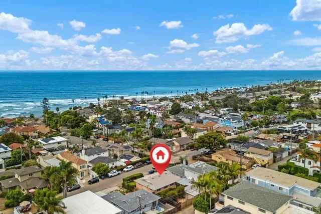 an aerial view of a city with lots of residential buildings and ocean view in back