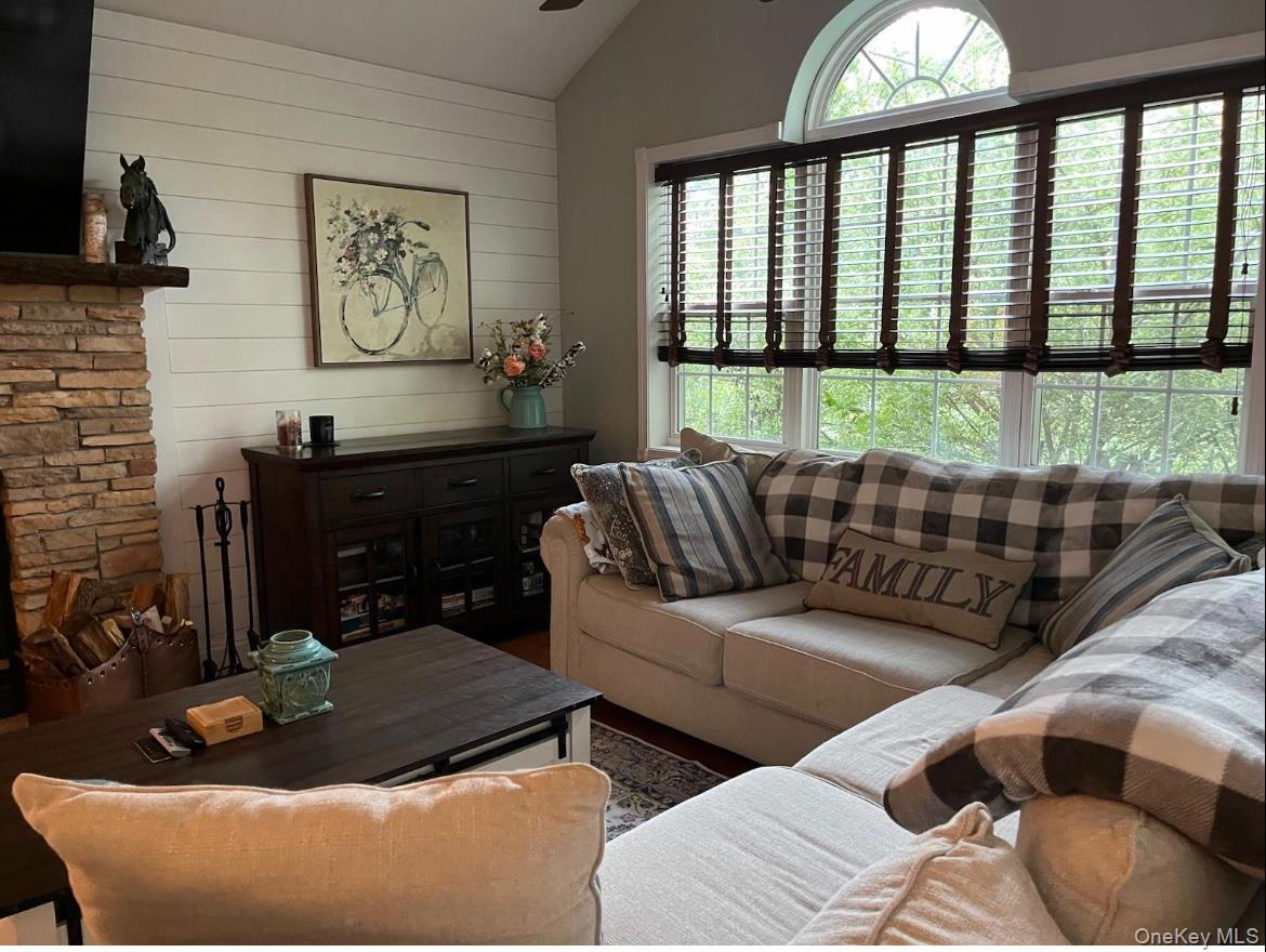 124 Rutsonville Road Wallkill, NY 12589 - Photo 25 of 33 Living area featuring a stone fireplace with a wood mantle, white shiplap wall, and a large window with an arched transom lets in all the light!
