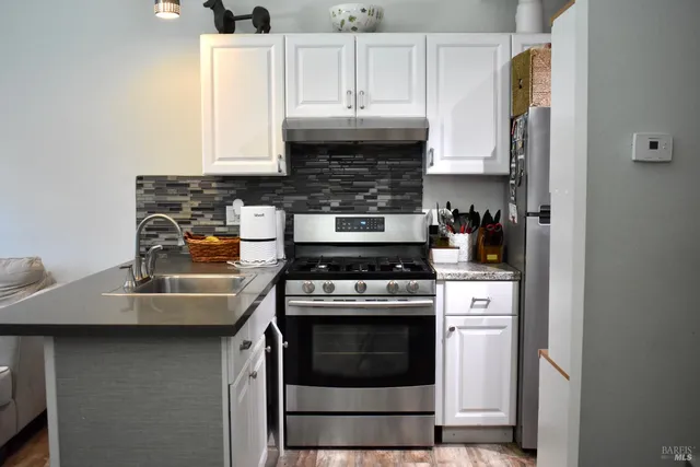 a kitchen with granite countertop a stove and a white cabinets