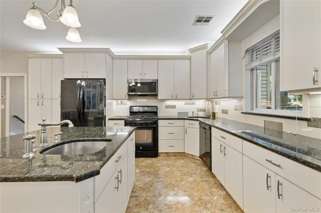 a kitchen with kitchen island granite countertop a sink a counter space appliances and cabinets
