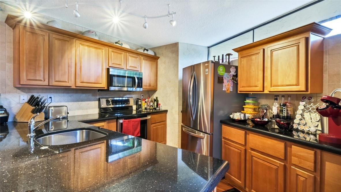 8146 Thames Boulevard, Unit A Boca Raton, FL 33433 - Photo 6 of 18 a kitchen with stainless steel appliances granite countertop a refrigerator and a stove top oven