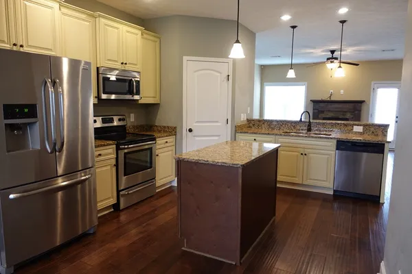 a kitchen with stainless steel appliances a refrigerator a stove a sink dishwasher a refrigerator and white cabinets with wooden floor