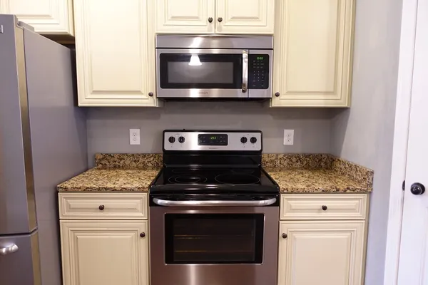 a kitchen with stainless steel appliances granite countertop white cabinets stove top oven and sink