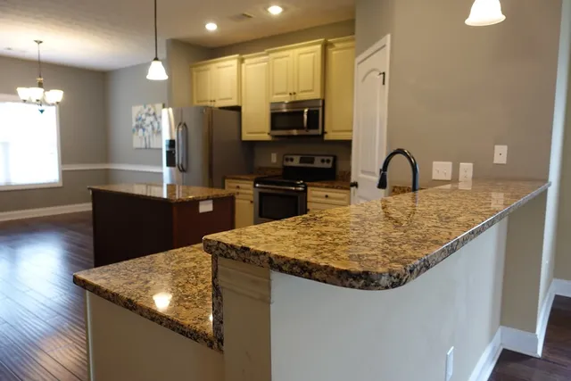 a kitchen with kitchen island granite countertop a sink stove and refrigerator