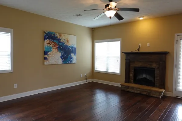 a view of a livingroom with wooden floor a ceiling fan and a fireplace