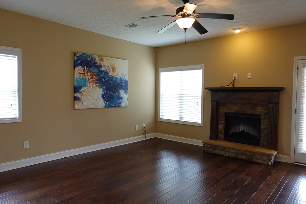 9981 Coppice Court Midland, GA 31820 - Photo 10 of 33 a view of a livingroom with wooden floor a ceiling fan and a fireplace