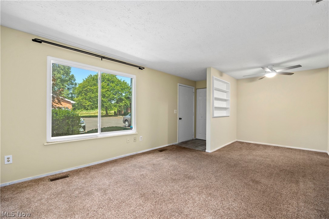 216 Moore Road Avon Lake, OH 44012 - Photo 5 of 22 Carpeted living space featuring a ceiling fan, a large window, and built-in shelving