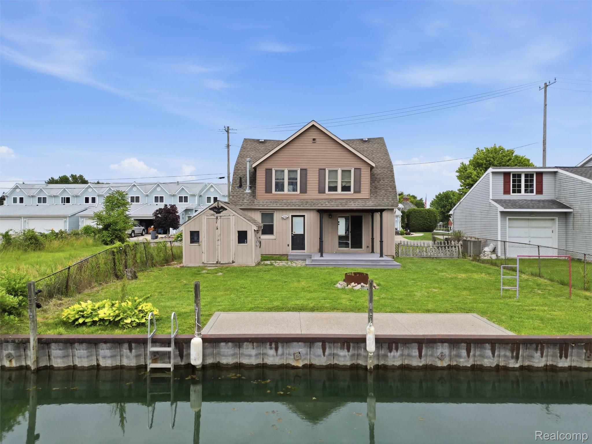 117 Kenyon Road Algonac, MI 48001 - Photo 4 of 47 Waterfront property featuring a private boat dock with ladder access, a spacious rear lawn, and a large elevated patio