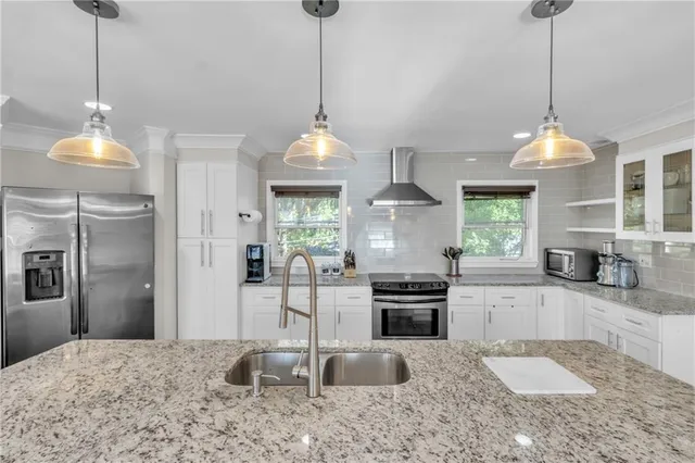 a kitchen with stainless steel appliances granite countertop a sink a stove and a wooden floor