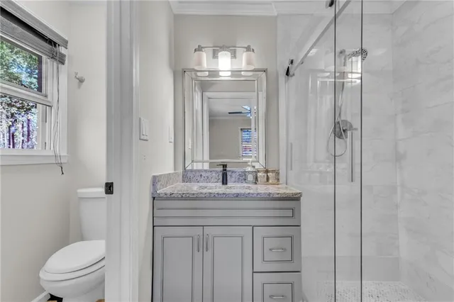 a bathroom with a granite countertop sink toilet a mirror and shower