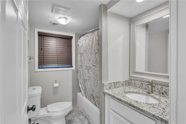 a bathroom with a granite countertop sink toilet a mirror a vanity and shower