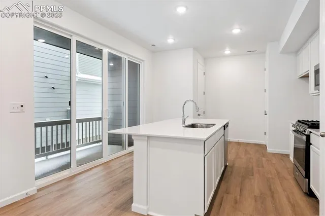 a kitchen with a sink a refrigerator and wooden floor