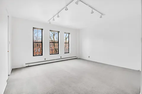 an empty room with windows and ceiling fan