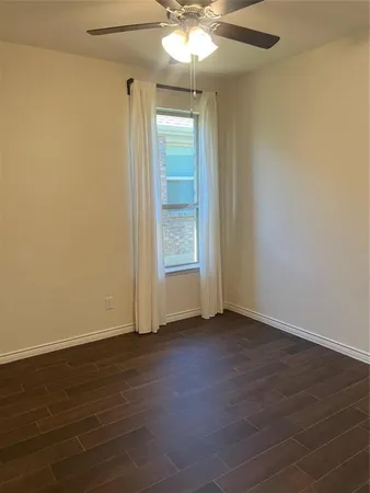 an empty room with wooden floor cabinet and windows