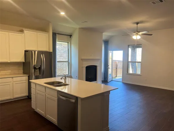 a kitchen with stainless steel appliances granite countertop a refrigerator a stove a sink dishwasher and a fireplace with wooden floor