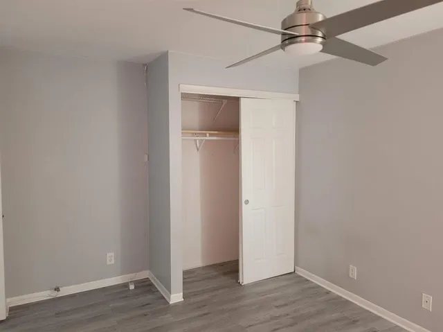an empty room with wooden floor closet and windows
