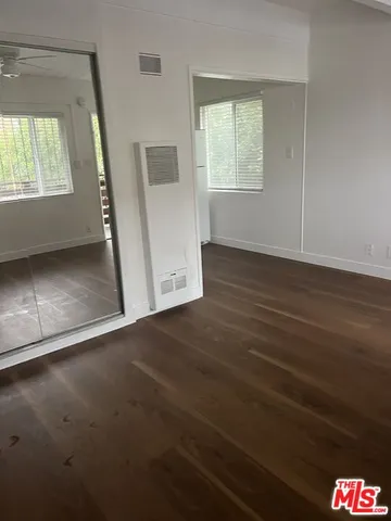 an empty room with wooden floor and fan