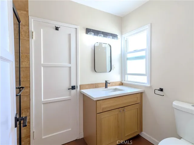 a bathroom with a toilet sink vanity and mirror