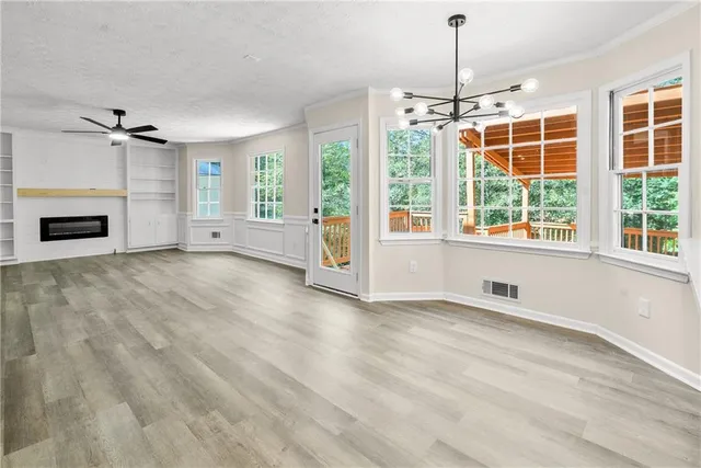 an empty room with windows chandelier and fireplace
