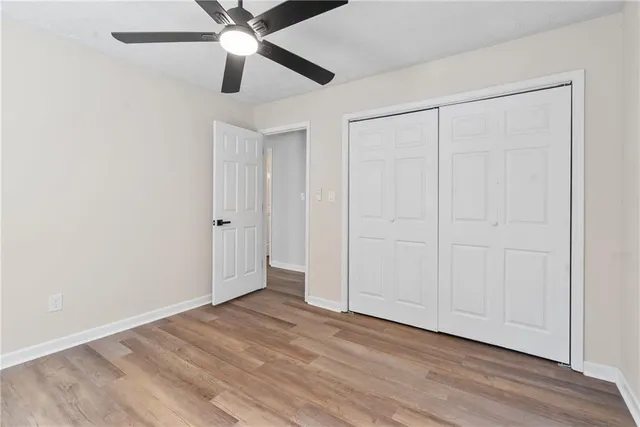 an empty room with wooden floor closet and ceiling fan