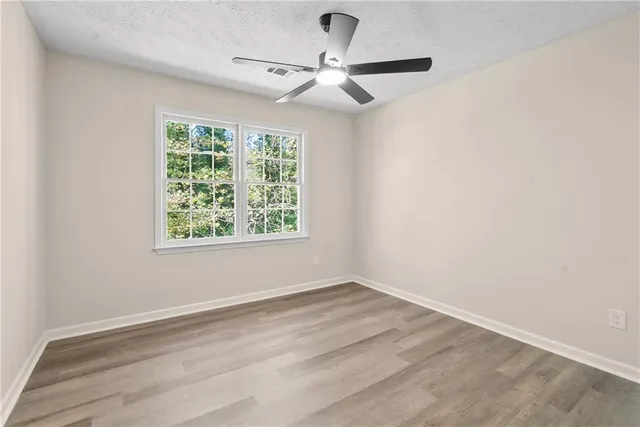 an empty room with a window and a fan
