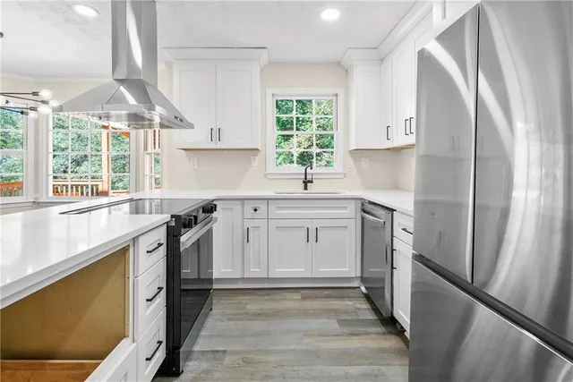 a kitchen with stainless steel appliances a sink cabinets and a window
