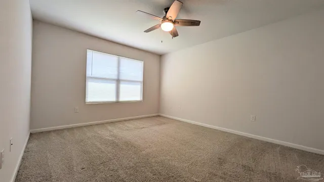 an empty room with windows and ceiling fan