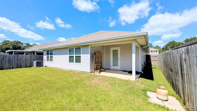 a view of a house with backyard and wooden fence