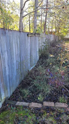 a view of a backyard with wooden fence and large trees