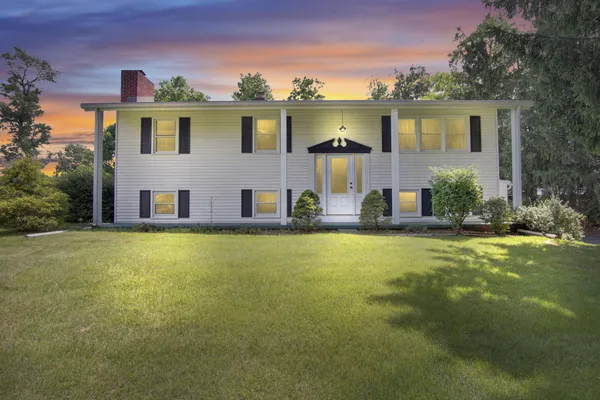 a front view of house with yard and trees in the background