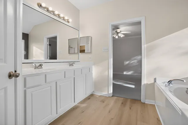 a bathroom with a double vanity sink a mirror and a bathtub