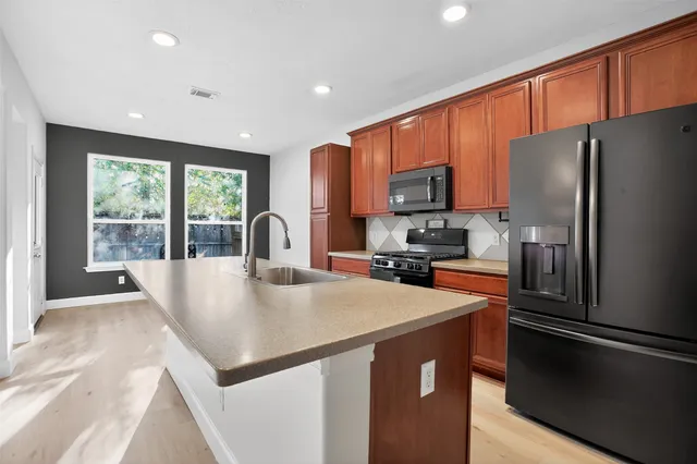 a kitchen with stainless steel appliances a refrigerator sink and wooden cabinets