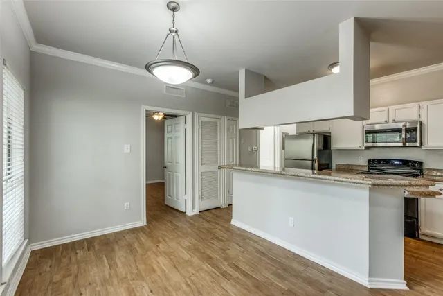 a kitchen with stainless steel appliances granite countertop a sink a stove a refrigerator and island with wooden floor