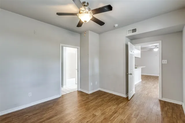 an empty room with wooden floor and a ceiling fan