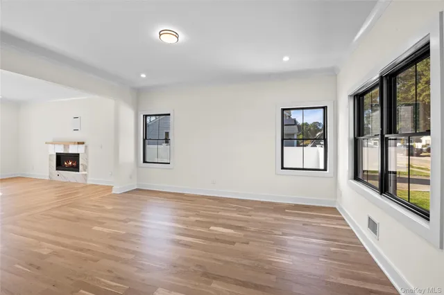a view of an empty room with a window and wooden floor