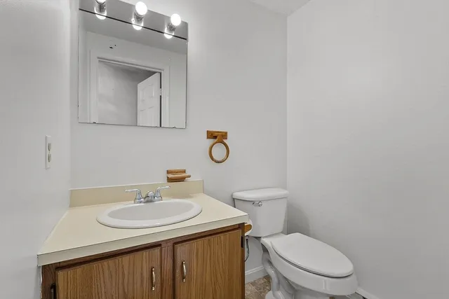 a bathroom with a toilet sink vanity and mirror