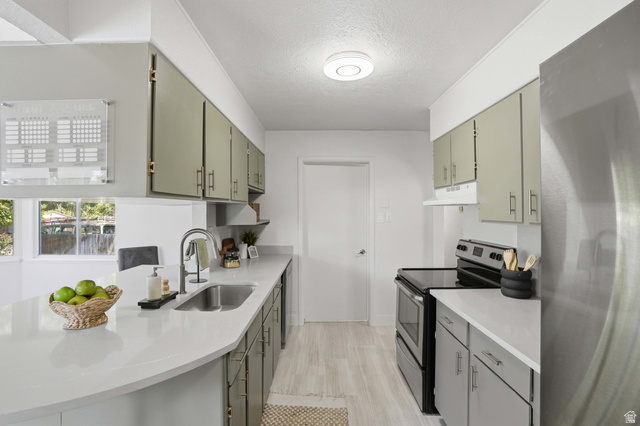 6889 South Village Road Salt Lake City, UT 84121 - Photo 14 of 44 Open-concept kitchen featuring light-toned cabinetry, a stainless steel sink with a gooseneck faucet, quartz countertops.