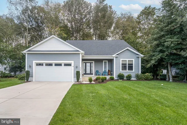 a front view of a house with a yard and trees