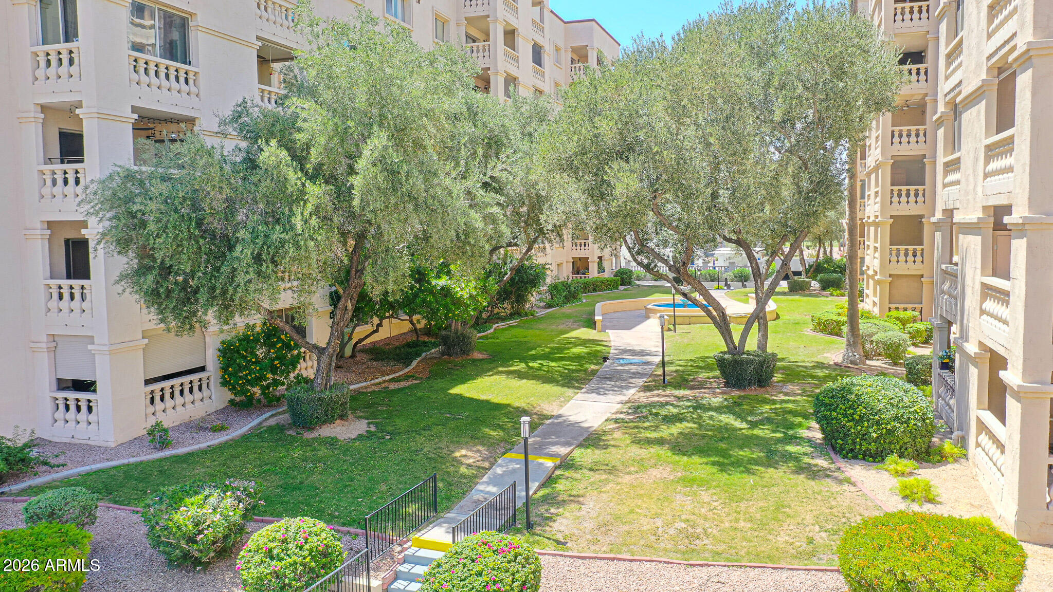 7920 East Camelback Road, Unit 111 Scottsdale, AZ 85251 - Photo 30 of 32 a view of backyard of white apartments with large trees and flower plants