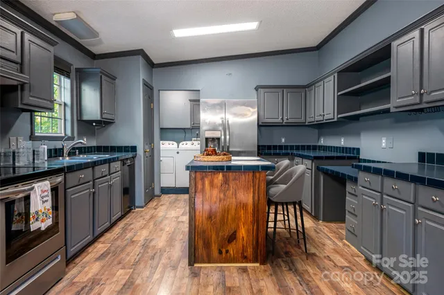 a kitchen with granite countertop wooden floors stainless steel appliances and a sink