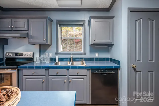 a kitchen with stainless steel appliances granite countertop a refrigerator a sink dishwasher a stove and a dining table with wooden cabinet