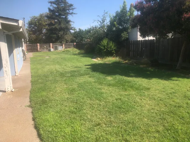 a backyard of a house with lots of green space and fountain