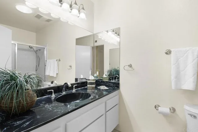 a bathroom with a granite countertop sink a mirror and a shower