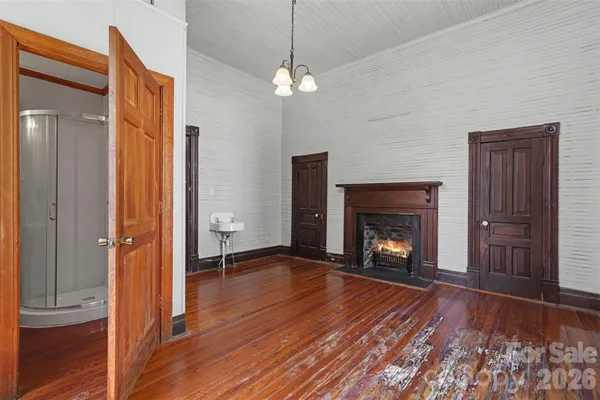 a view of an empty room with wooden floor fireplace and a window
